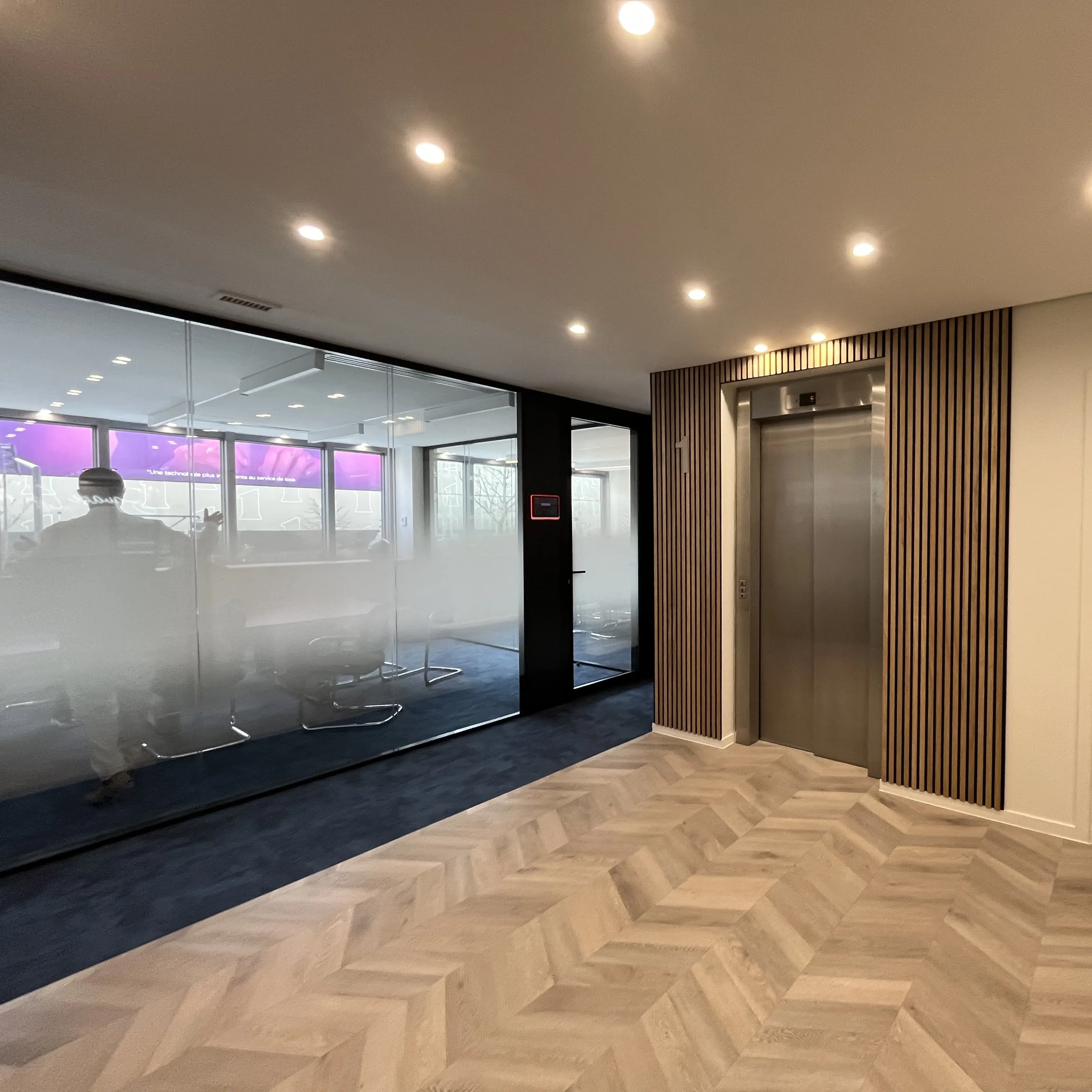 Palier ascenseurs avec vue sur open space avec vitrophanie