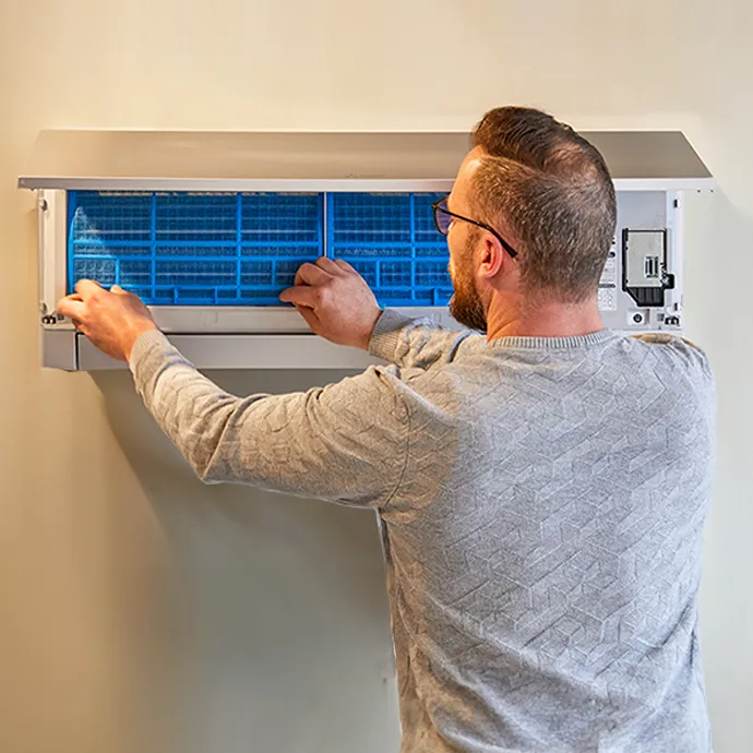 Image qui montre une personne qui nettoie les filtres d'une pompe à chaleur