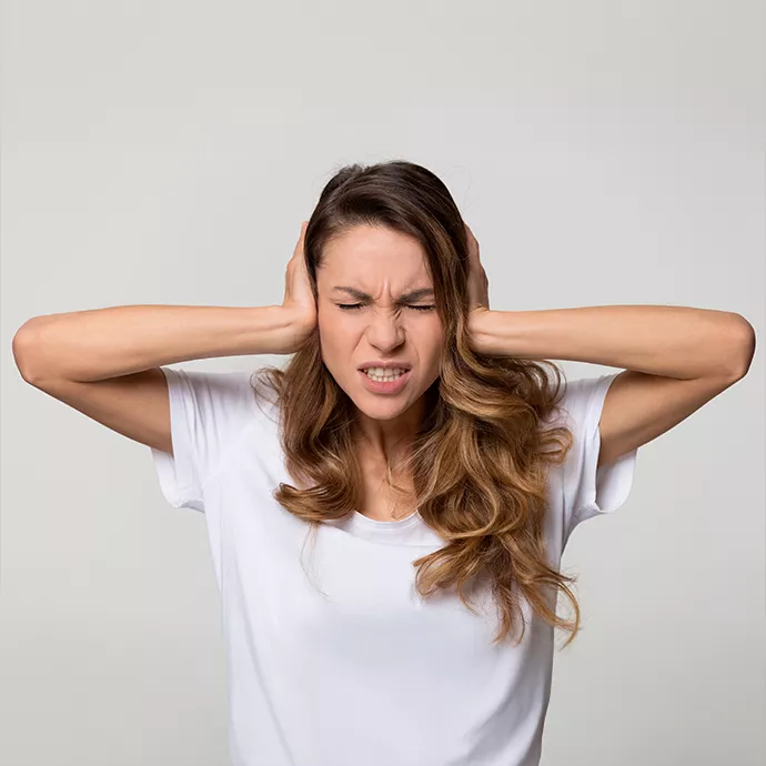 Image qui montre une femme qui se bouche les oreilles à cause des nuisances sonores d'une pompe à chaleur